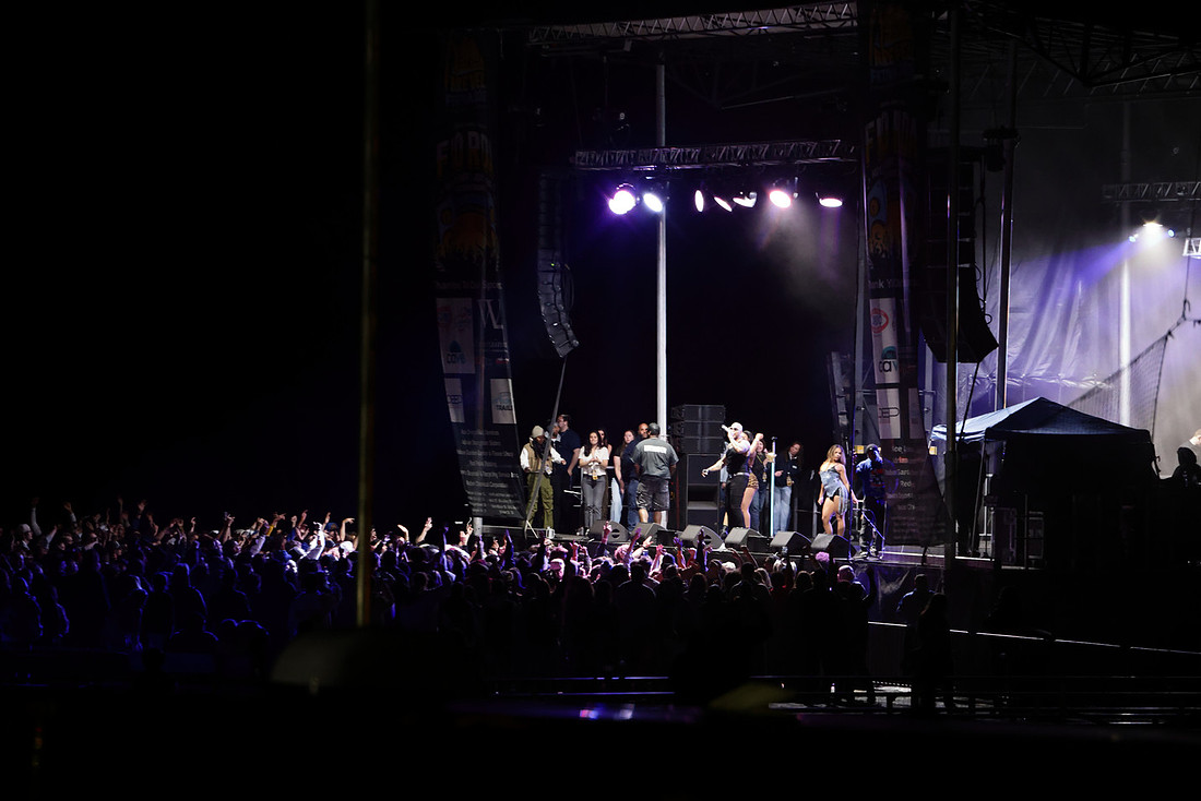 A main stage lit at night with a large crowd in front of it