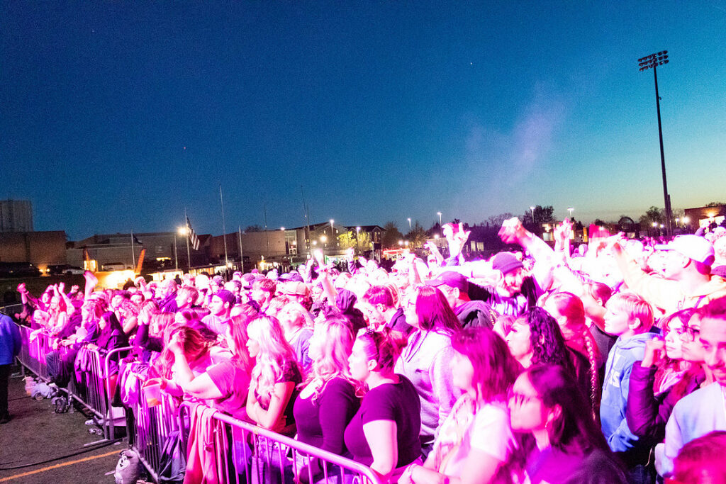 A large crowd at the barricade, lit by stage lighting at dusk