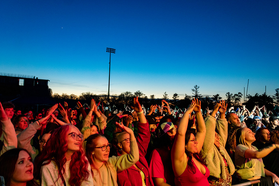 A festival crowd reaching up toward the Farewell Festival stage at dusk