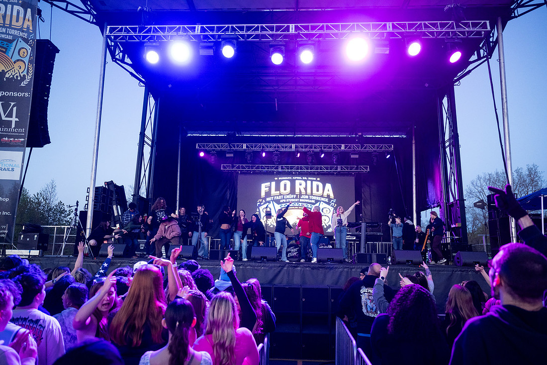 A crowd watches performers on a festival main stage at dusk