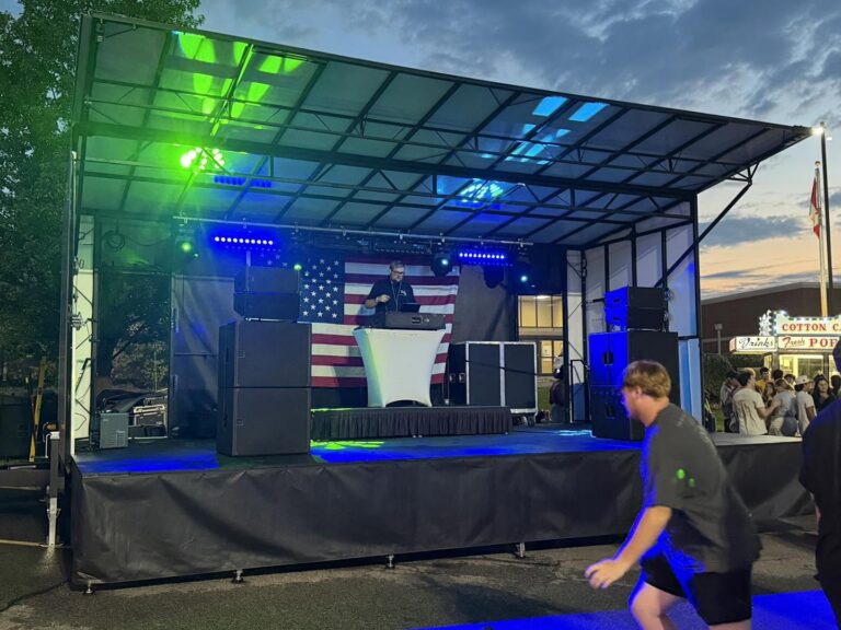 Mobile stage lit in green and blue for an evening event at Adrian College