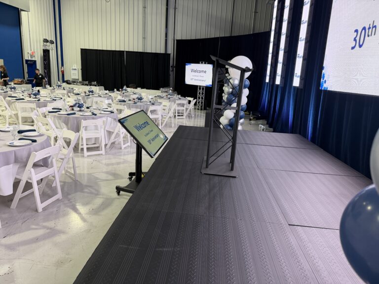 View from the stage across the tables, with a confidence monitor and a relay screen