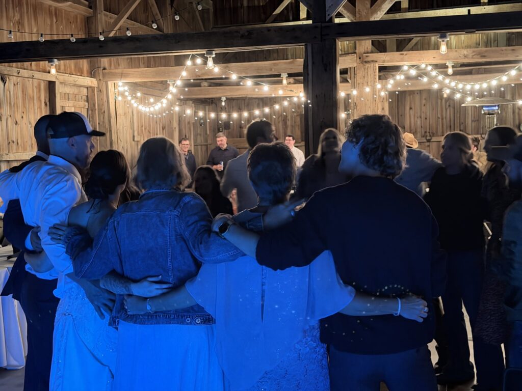 Wedding guests on the dance floor under string lights in a barn